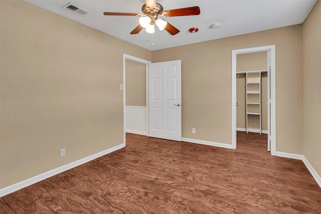 unfurnished bedroom with dark wood finished floors, a closet, visible vents, a spacious closet, and baseboards