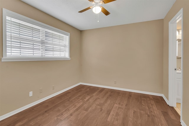 empty room with ceiling fan, wood finished floors, and baseboards