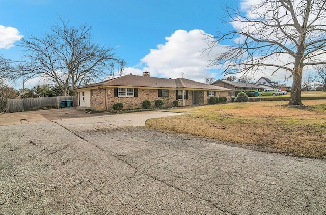 view of front of property with a chimney, fence, concrete driveway, and brick siding