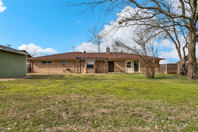 rear view of house featuring brick siding, a chimney, fence, and a yard