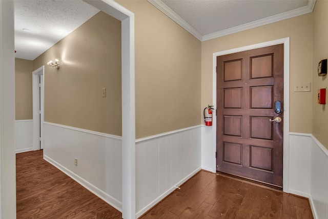 foyer entrance featuring a wainscoted wall, crown molding, a textured ceiling, and wood finished floors