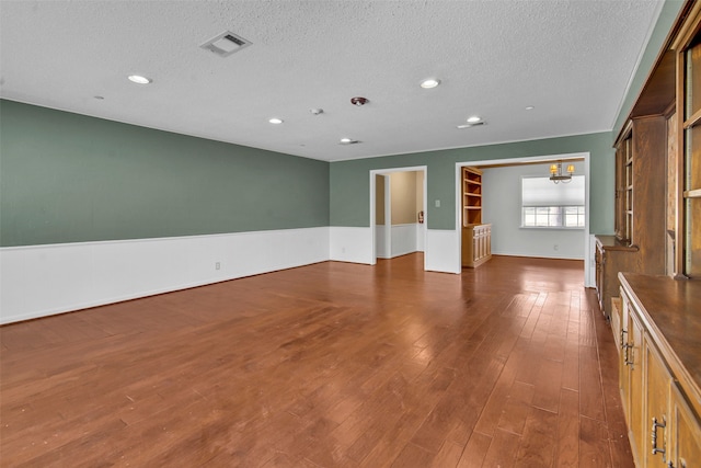 empty room with dark wood finished floors, recessed lighting, visible vents, a textured ceiling, and a chandelier