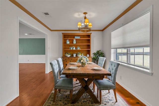 dining space featuring a chandelier, wood finished floors, visible vents, and crown molding