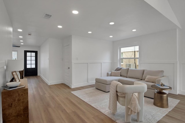 living area with a decorative wall, plenty of natural light, recessed lighting, and light wood-style floors