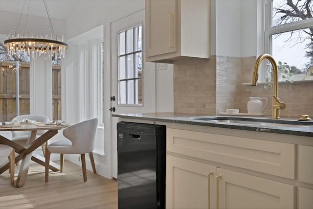 kitchen with light wood-style flooring, black dishwasher, a sink, and backsplash