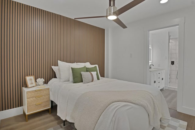 bedroom featuring recessed lighting, ceiling fan, ensuite bath, wood finished floors, and baseboards