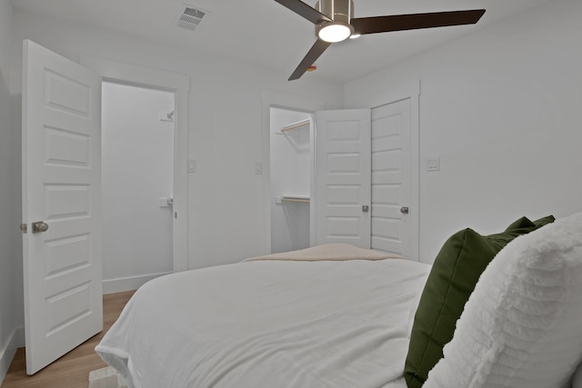 bedroom featuring baseboards, ceiling fan, visible vents, and wood finished floors