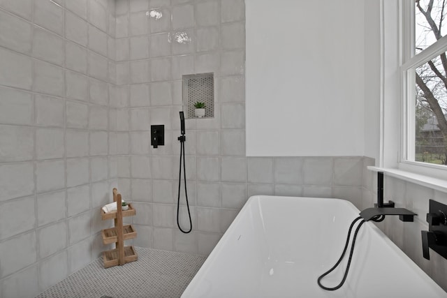 bathroom featuring a soaking tub, plenty of natural light, tiled shower, and tile walls