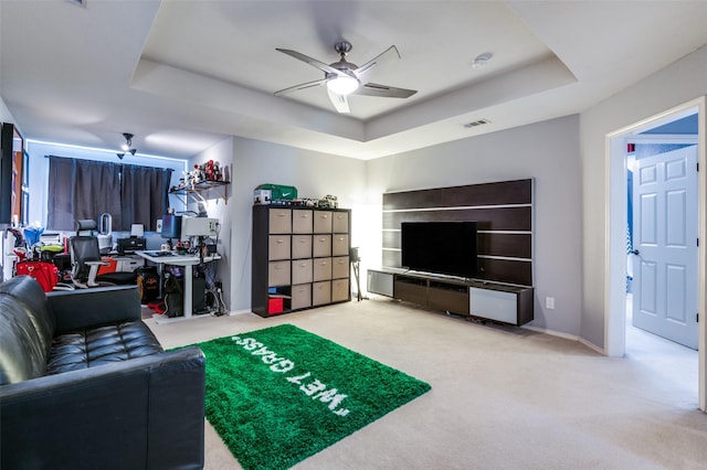 carpeted living area with visible vents, ceiling fan, baseboards, and a tray ceiling