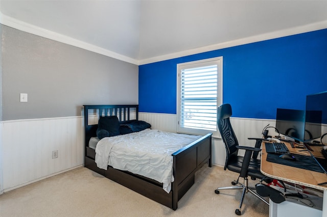 carpeted bedroom featuring a wainscoted wall and lofted ceiling