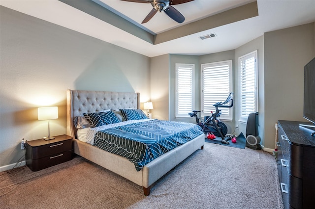 carpeted bedroom featuring visible vents, a ceiling fan, a raised ceiling, and baseboards