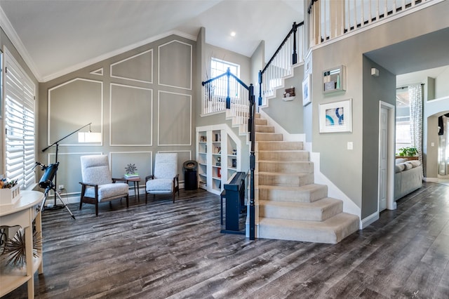 interior space featuring high vaulted ceiling, wood finished floors, stairway, crown molding, and baseboards