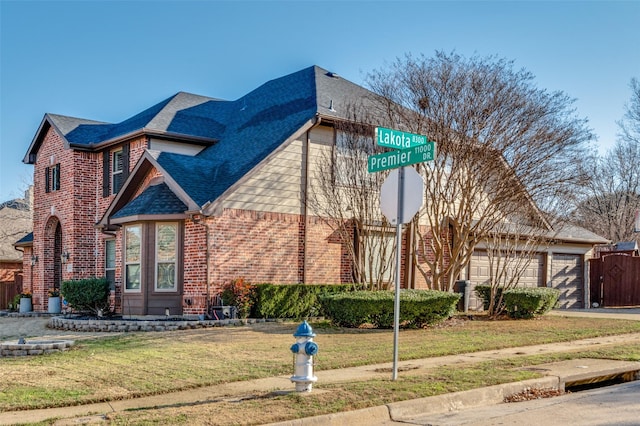 view of front of property featuring brick siding, driveway, a front lawn, and roof with shingles