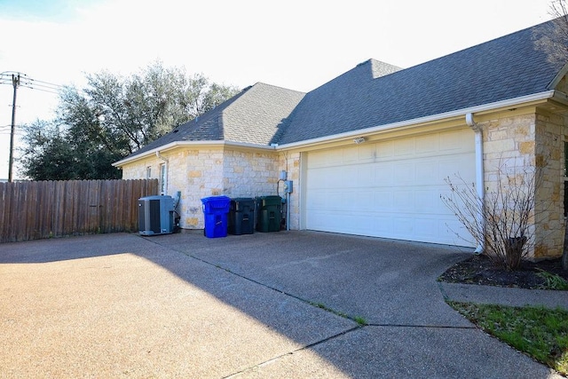 view of side of property with concrete driveway and stone siding