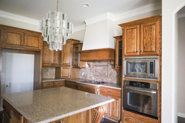 kitchen with ornamental molding, appliances with stainless steel finishes, brown cabinets, and an inviting chandelier