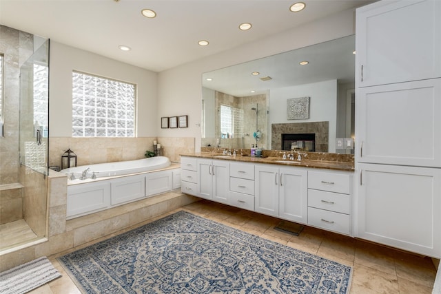 bathroom featuring double vanity, a stall shower, a garden tub, a sink, and recessed lighting