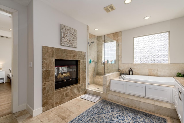 ensuite bathroom with visible vents, a tile fireplace, ensuite bath, a garden tub, and a tile shower