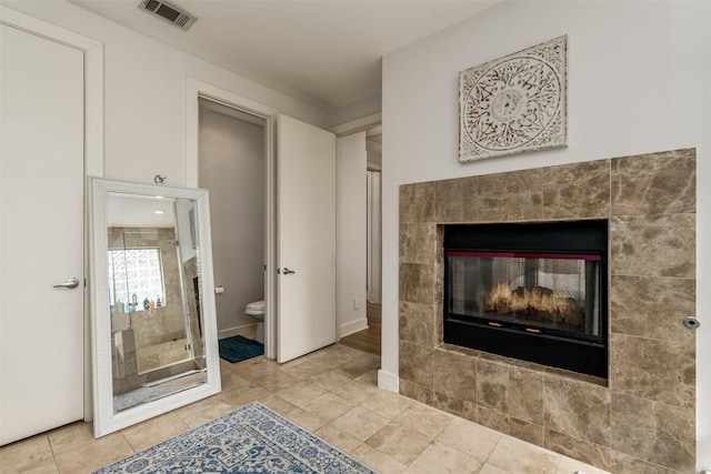 full bathroom with visible vents, toilet, tile patterned flooring, a shower stall, and a fireplace