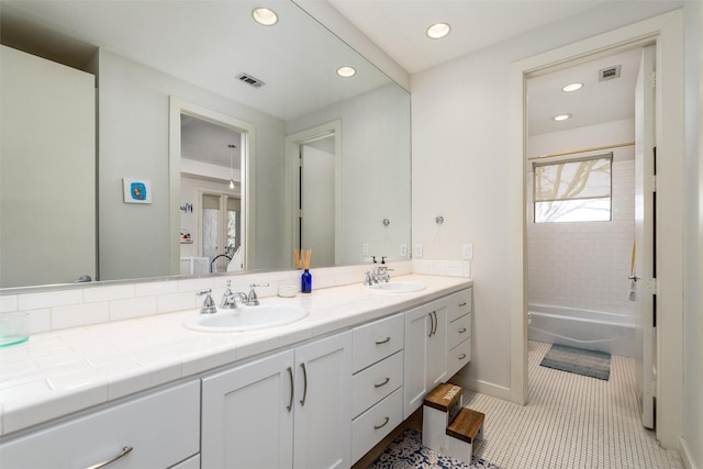 bathroom featuring double vanity, a sink, visible vents, and tile patterned floors