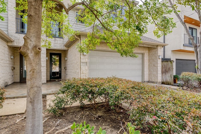 doorway to property with a shingled roof and a garage