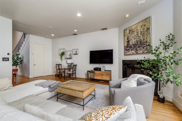 living area with stairway, wood finished floors, visible vents, and recessed lighting