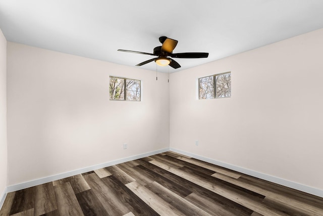 empty room with dark wood-style floors, baseboards, and a ceiling fan