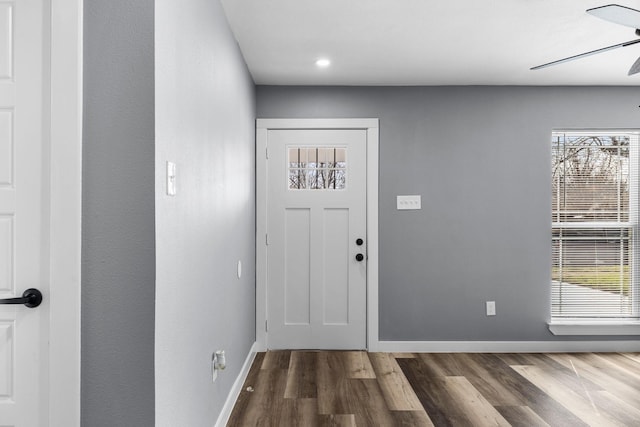 foyer featuring a healthy amount of sunlight, baseboards, dark wood finished floors, and a ceiling fan