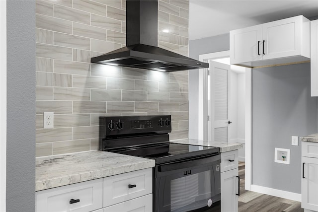 kitchen featuring black electric range, decorative backsplash, white cabinetry, wood finished floors, and wall chimney exhaust hood