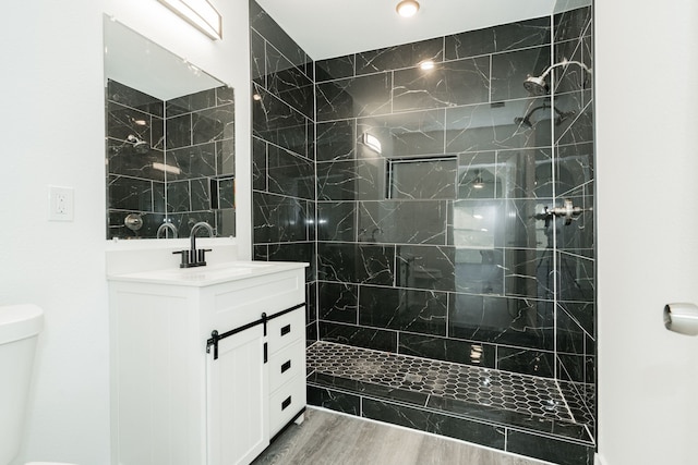 full bath featuring wood finished floors, vanity, toilet, and walk in shower