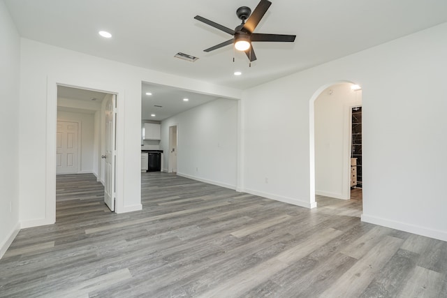 empty room featuring arched walkways, recessed lighting, a ceiling fan, visible vents, and light wood-type flooring