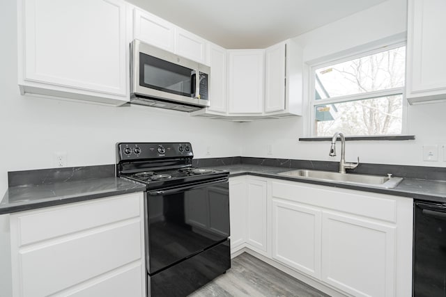 kitchen with black electric range, dark countertops, stainless steel microwave, and a sink