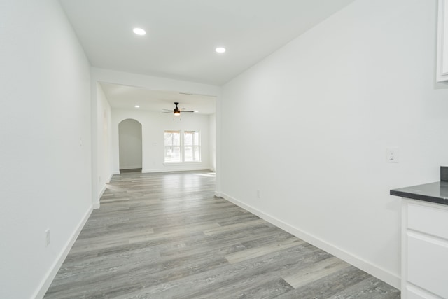 interior space featuring light wood-style floors, arched walkways, baseboards, and recessed lighting