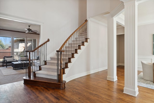 stairway featuring a ceiling fan, ornate columns, and wood finished floors