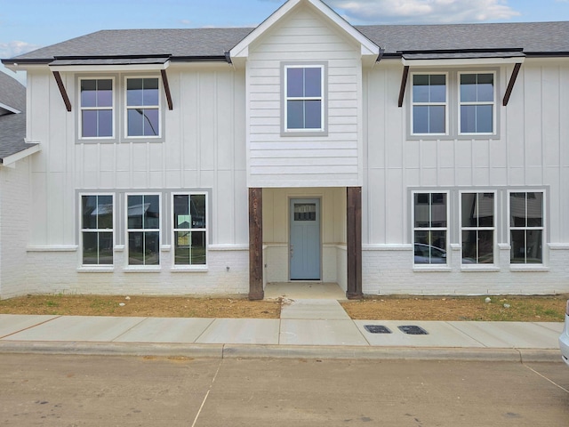 multi unit property featuring board and batten siding, brick siding, and roof with shingles