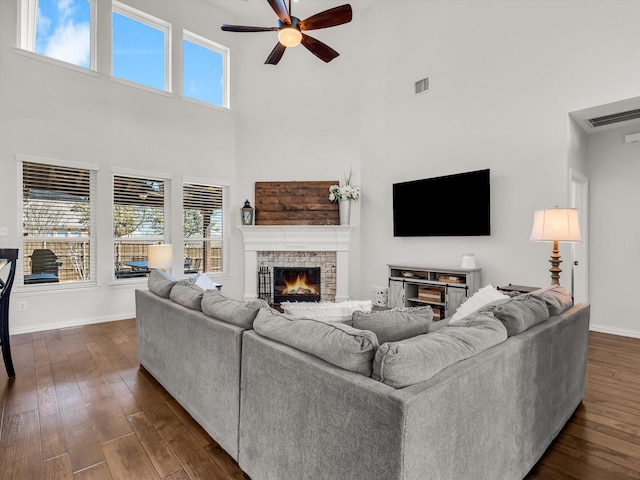 living area featuring visible vents, a ceiling fan, dark wood finished floors, a fireplace, and baseboards