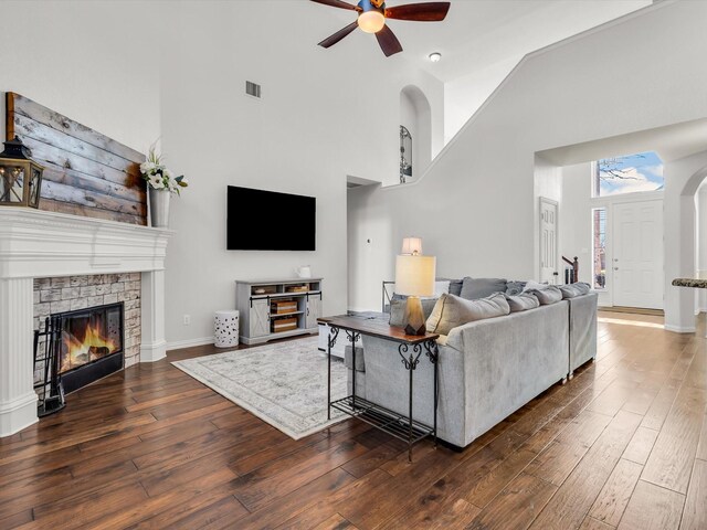 living room featuring a glass covered fireplace, visible vents, ceiling fan, and hardwood / wood-style flooring