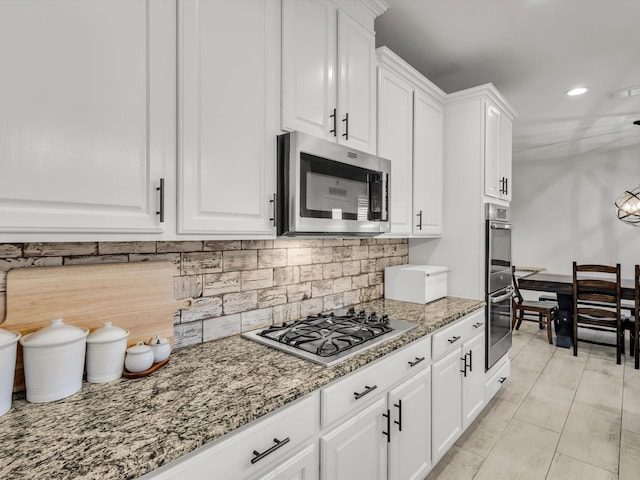 kitchen featuring backsplash, appliances with stainless steel finishes, white cabinetry, and light stone countertops