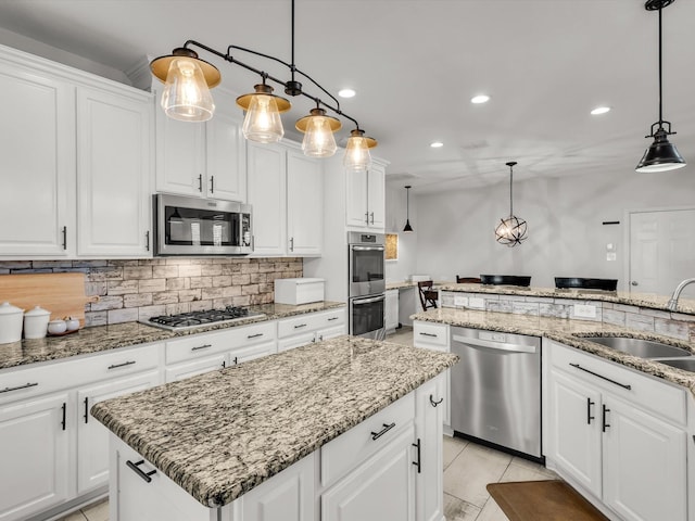 kitchen with recessed lighting, a sink, appliances with stainless steel finishes, tasteful backsplash, and a center island