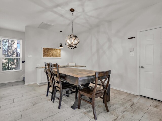 dining space featuring baseboards, a chandelier, and wood tiled floor