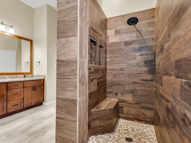 full bath with a tile shower and vanity