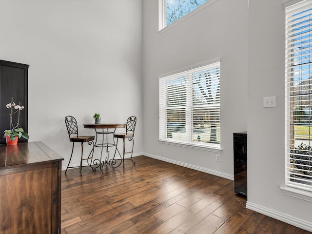 dining area featuring dark wood finished floors, a high ceiling, and baseboards