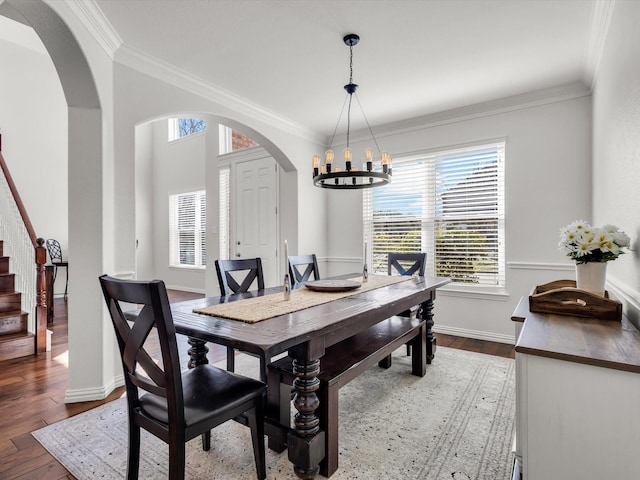 dining area featuring arched walkways, a notable chandelier, stairs, and dark wood-type flooring