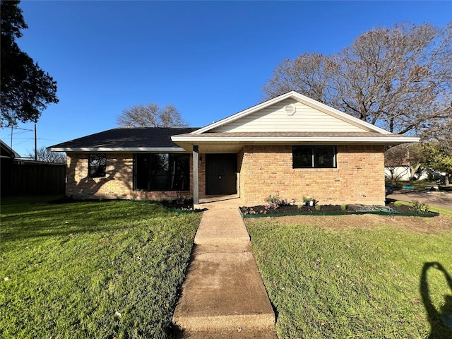 ranch-style home with brick siding, a front yard, and roof with shingles