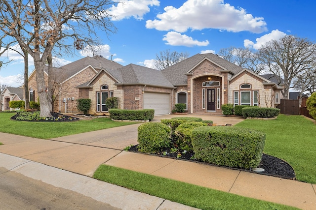 french country style house featuring brick siding, a shingled roof, a front yard, driveway, and an attached garage