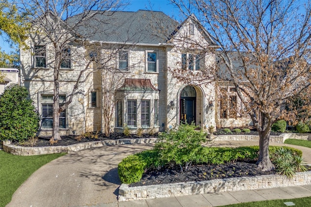 view of front facade with stone siding and aphalt driveway