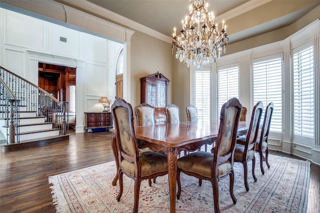 dining space with a chandelier, a decorative wall, wood finished floors, stairs, and ornamental molding