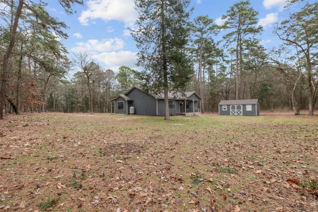 view of yard featuring an outbuilding, a forest view, and a shed