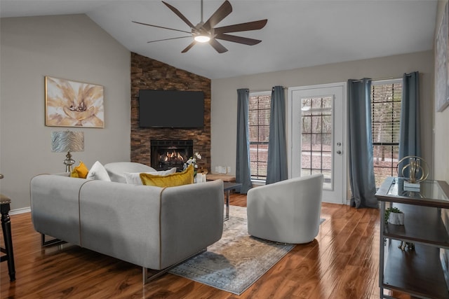 living area featuring a fireplace, a ceiling fan, vaulted ceiling, and wood finished floors