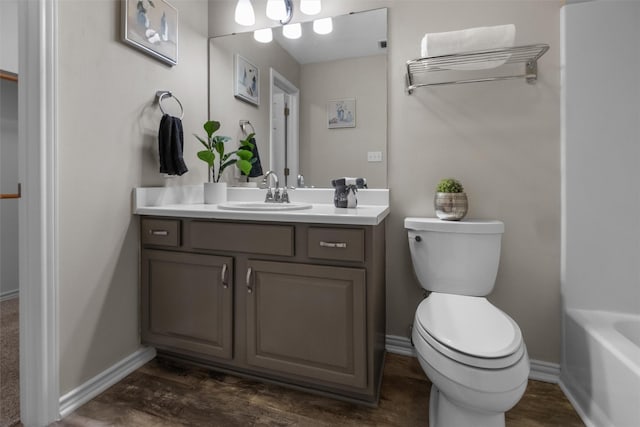 full bathroom featuring a tub to relax in, vanity, toilet, and wood finished floors