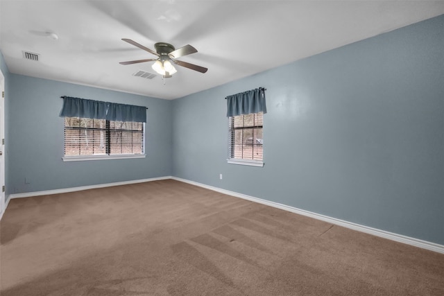 empty room featuring carpet floors, baseboards, visible vents, and a ceiling fan